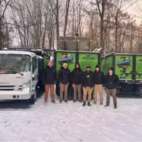 Ohio Junk Force team members stand together before a green truck, showcasing teamwork and camaraderie.