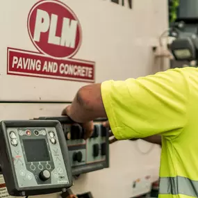 Employee in front of a machine with the PLM Paving and Concrete logo