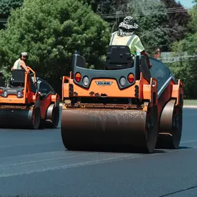 2 PLM Paving and Concrete employees operating asphalt rollers