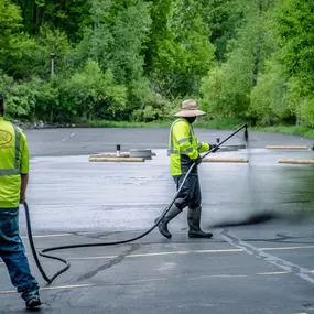 2 PLM Paving and Concrete employees sealcoating a parking lot