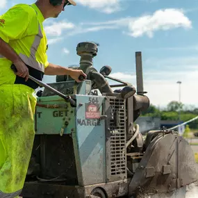 plm paving employee operating a saw cutting machine