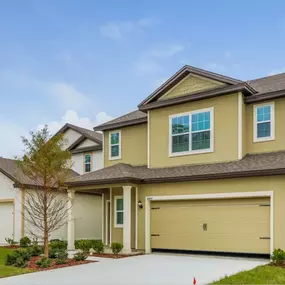 Treeline trails apartment with beige siding, double garage, and landscaped front yard