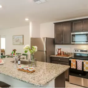 modern kitchen featuring dark wooden cabinets, polished granite countertops, and stainless steel appliances