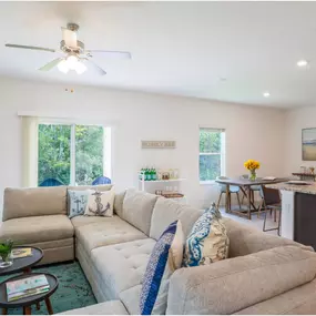 beautifully designed open-concept living space with a large beige sectional sofa adorned with nautical-themed pillows