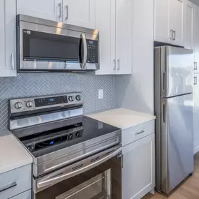 A kitchen with a stove top oven, microwave, and refrigerator.