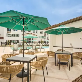 A patio with a table and chairs under a green umbrella.