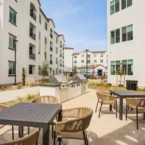 A patio with a table and chairs is surrounded by apartment buildings.