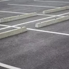 Wheel Stop Installation in parking lot in Dallas-Fort Worth featuring newly installed concrete wheel stops designed to prevent vehicles from moving too far forward, protecting sidewalks, curbs, and nearby structures while ensuring ADA compliance and pedestrian safety.