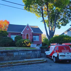 zhumas construction van parked in the driveway of a brick house