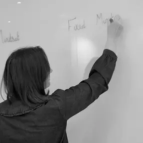 Lisa Powell is focused on writing on a whiteboard, with her back to the camera. Her precise and thoughtful approach to teaching is captured in this moment, as she prepares a lesson.