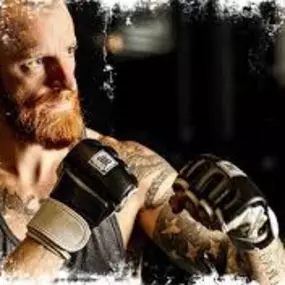 A man with a determined look is preparing to throw a punch during a Jabz Boxing session. Wearing gloves, he embodies the strength and focus participants can achieve through the program. The gritty, high-energy aesthetic reflects the spirit of the gym.