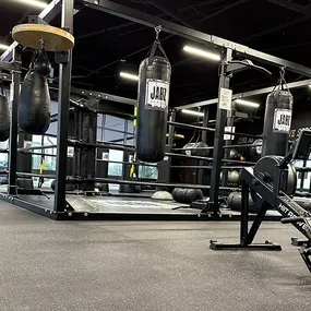 The interior of Jabz Boxing, showcasing a custom boxing ring surrounded by heavy bags, rowing machines, and fitness equipment. The clean and modern design highlights the gym’s focus on high-quality facilities and an immersive workout experience.