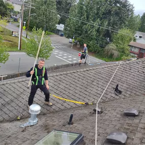 A man on a roof, highlighting the clean and well-maintained surface after roof cleaning.