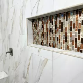 This is what thoughtful bathroom remodeling looks like. Clean lines, beautiful contrast, and a custom touch that makes the space feel truly elevated. Ledezma Remodeling brought this shower wall to life with rich, mosaic tile accents and sleek marble-look walls that blend style and function seamlessly.