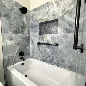 This sleek bathtub remodel by Ledezma Remodeling combines striking stone-look tile with matte black fixtures for a bold, modern upgrade. The recessed niche and clean lines add both style and function, creating a space that’s calm, practical, and beautifully finished. Every detail is thoughtfully crafted to elevate the everyday experience.