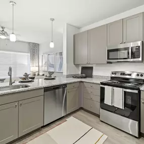 First-floor kitchen and living room with wood-style flooring and taupe cabinets at Camden Leander apartments in Leander, Tx