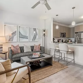 First-floor living room and kitchen with wood-style floors and extended kitchen counter at Camden Leander apartments in Leander, Tx