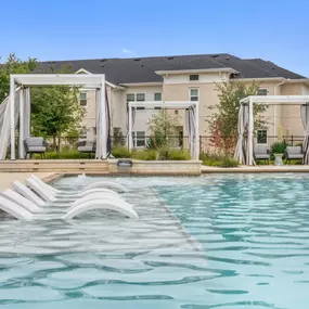 Resort-style pool tanning ledge with in-water loungers at Camden Leander apartments in Leander, Tx