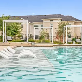 Resort-style pool tanning ledge with in-water loungers at Camden Leander apartments in Leander, Tx