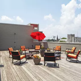 a rooftop patio with a red umbrella and chairs on a roof