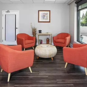 a living room with orange chairs and a table and a window