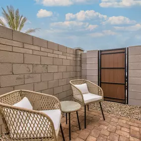 a patio with two chairs and a table next to a brick wall