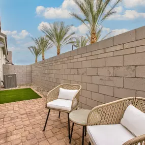 a patio with two chairs and a table next to a wall