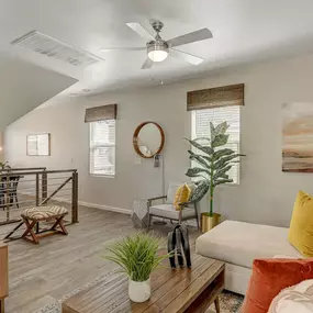 A living room with a white couch, a wooden coffee table, and a ceiling fan