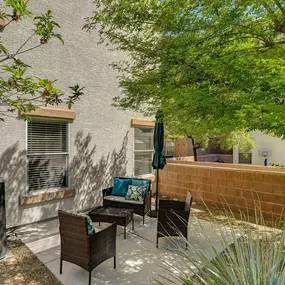 A patio with a table and chairs is surrounded by trees