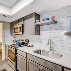 A modern kitchen with stainless steel appliances and a white tiled backsplash