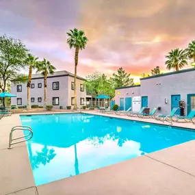A swimming pool surrounded by lounge chairs and palm trees