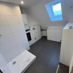 Handwerksarbeiten im Rahmen einer Badezimmersanierung: Fliesenleger bei der fachgerechten Verlegung von großformatigen Wandfliesen. Die Ausführung erfolgt sauber und präzise, typischer Einsatzbereich im modernen Innenausbau.