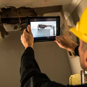 ServiceMaster technician taking a photo of a roof leak