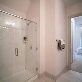 A modern shower area at Tindall Park at SouthPark Apartments with sleek tile walls and glass doors.