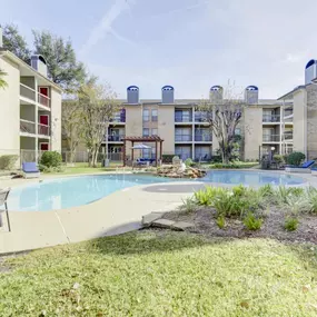 A refreshing swimming pool at Magnolia Terrace Apartments in Houston, surrounded by picnic spaces and seating areas.