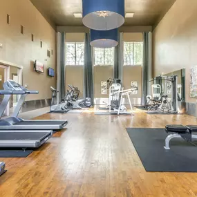 A modern fitness gym at Gramercy Park Apartments in Houston with a variety of exercise equipment.