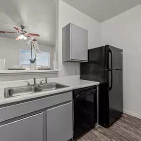 A kitchen sink area at Huntington Meadows Apartments in Austin with a basic countertop and refrigerator.