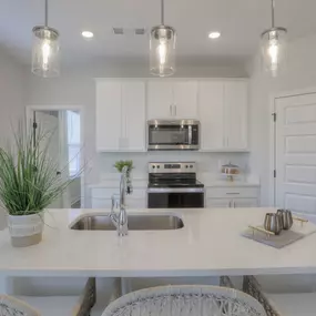 Open concept kitchen with quartz countertops, stainless steel appliances, and spacious pantry.