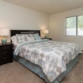 A bedroom with a bed, nightstand, and two lamps