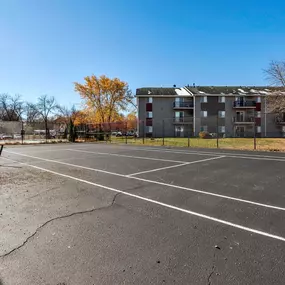 an empty parking lot with an apartment building in the background