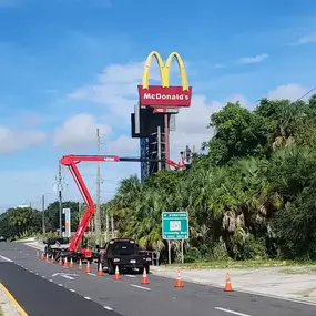 Precision tree trimming near commercial signage using a high-reach lift.