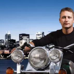 A motorcycle driver with new motorcycle insurance in front of the Chicago skyline