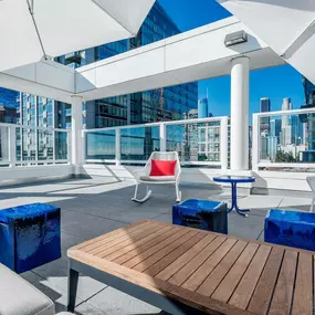 A wooden table is in the middle of a patio with white chairs and umbrellas.