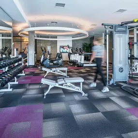 A gym with a variety of equipment including treadmills, weights, and exercise machines