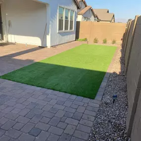 Low-maintenance artificial turf and paver combination for a modern backyard. Enjoy a lush, green lawn without the hassle of watering or mowing.