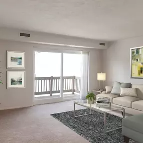 A living room with a grey couch, a coffee table, and a painting on the wall