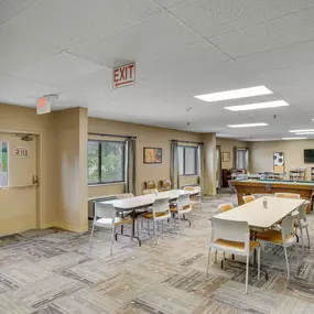 A room with tables and chairs and an exit sign on the ceiling
