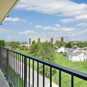 A balcony overlooks a residential area with houses and apartment buildings