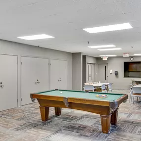 A pool table in a room with a carpeted floor and white walls
