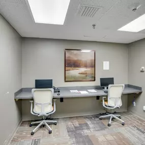 A room with a poster on the wall and two chairs in front of a desk